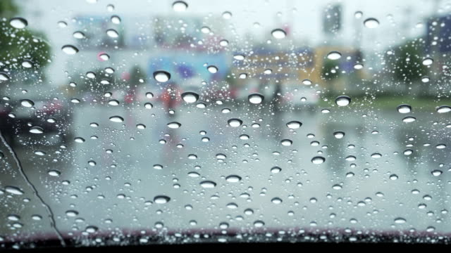 Car-windshield-with-rain-drops-during-heavy-traffic-downtown