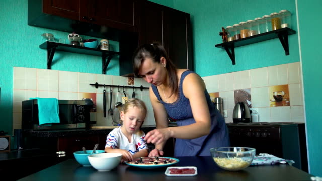 Mutter-und-Tochter-legte-Oliven-auf-dem-Pizzaboden