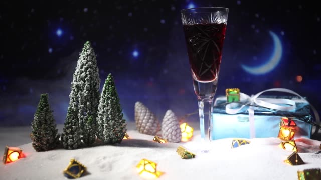 Glas-Wein-mit-Weihnachtsdekoration.-Rotwein-in-Kristall-Glas-auf-Schnee-mit-kreativen-Neujahr-Kunstwerk.-Textfreiraum