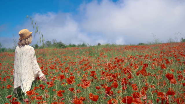 Mature-woman-enjoying-the-beauty-of-nature-on-a-colorful-poppy-field