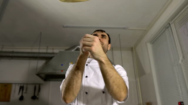 Cook-in-the-kitchen-preparing-pizza-dough,-juggling-them-with-his-hands