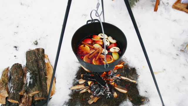 Cocinar-el-vino-caliente-en-la-hoguera-en-el-bosque-de-invierno.