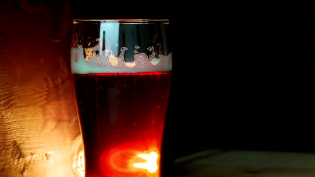 fresh-beer-with-foam-into-drink-pint-glass-with-ice-frozen-drops,-on-gold-brown-background,-fun-and-nutrition-drink