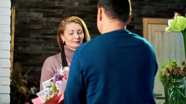 Woman-florist,-gives-a-bouquet-of-flowers-to-the-customer.