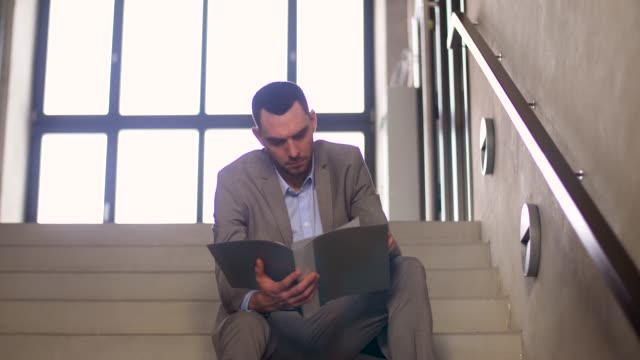businessman-with-folder-sitting-on-stairs