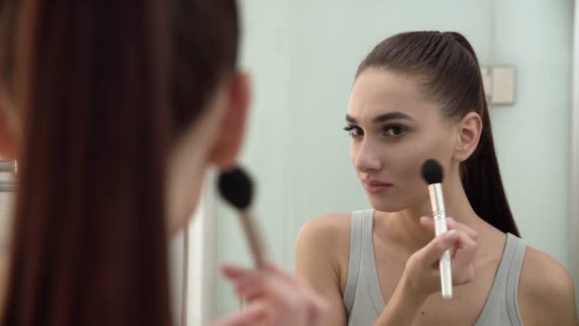 Face-Makeup.-Woman-Using-Powder-And-Looking-In-Mirror