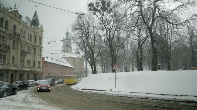 LVOV,-Ucrania---Timelapse-de-invierno-2018:-El-tiempo-nevoso-en-la-vieja-ciudad-de-Lviv-en-Ucrania.-Personas-están-caminando-por-la-calle.-Paseo-en-coches,-autobuses-y-tranvías-a-lo-largo-de-la-carretera.
