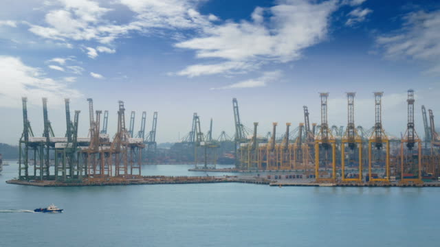 4-K.-Singapur-Hafen-mit-Frachtschiff-Segeln-langsam-auf-das-Meer-und-viele-Container-und-gelb-Kräne-im-Hintergrund