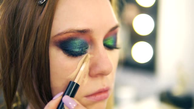 Make-up-Artist-Anwendung-Stiftung-auf-junge-Frau-Gesicht-mit-Pinsel,-legt-es-auf-eine-Nase-und-Wange.-Seitenansicht