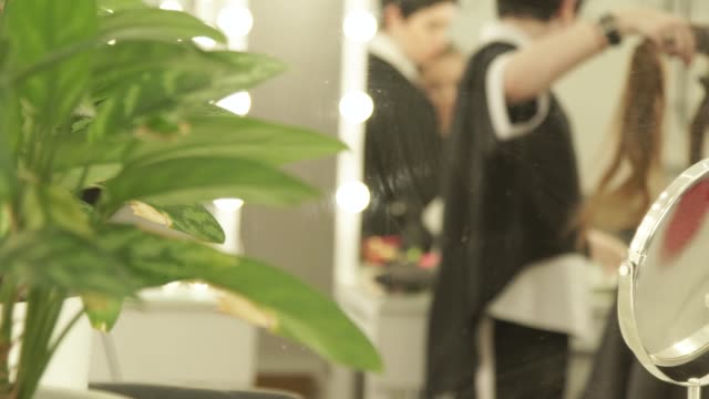Reflexion-im-Spiegel-Haircutter-weibliche-Haare-zu-kämmen,-beim-Haareschneiden-im-Beauty-Salon.-Friseur-Friseursalon-weibliche-Frisur-Bei