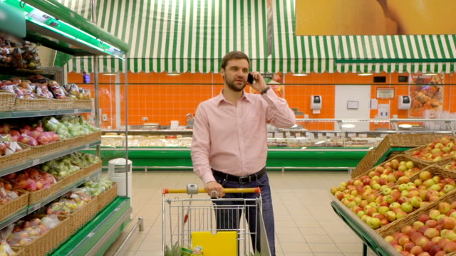 Hombre-al-cliente-mediante-teléfono-móvil-en-el-mercado-de-alimentos