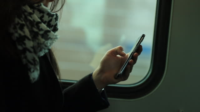 Primer-plano-de-mujer-sosteniendo-el-dispositivo-smartphone-mientras-viaja-en-tren.-Persona-navegando-por-internet-y-revisar-correos-electrónicos