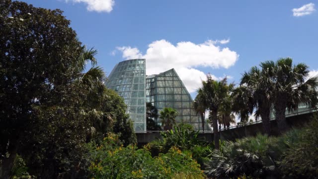 Low-Angle-Panning-Video-of-Cone-Shape-Glass-Greenhouse-Behind-Trees-Close-Up