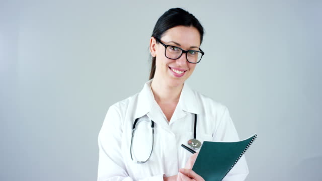 Retrato-de-un-mujer-médico-con-bata-blanca-y-estetoscopio-sonriendo-mirando-en-cámara-sobre-fondo-blanco.