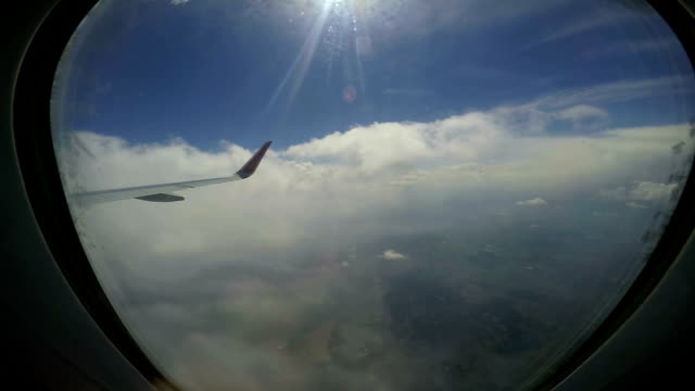 Flugzeugflügel-fliegen-durch-die-Wolken-über-der-Stadt
