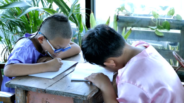 Feliz-niño-Asiático-con-escribir-en-el-cuaderno-y-lápices-de-dibujo-en-casa.-concepto-de-educación