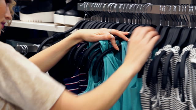 Einkaufen,-Mode,-Stil-und-Menschen-Konzept.-Frauen-die-Wahl-Kleid-in-Einkaufszentrum-oder-Bekleidungsgeschäft-einkaufen.