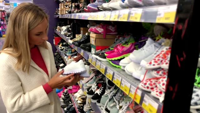 mujer-buscando-zapatos-de-los-cabritos-en-la-tienda