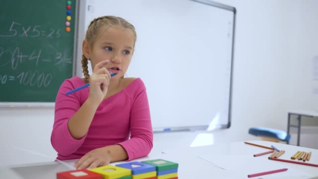 Schultag,-weibliche-Schüler-schreibt-eine-Aufgabe-in-Heft-an-der-Rezeption-in-einem-Klassenzimmer-auf-Hintergrund-von-blackboard