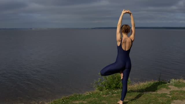 Yoga-Woman-Sportswear-gegen-See,-Ansicht-von-hinten
