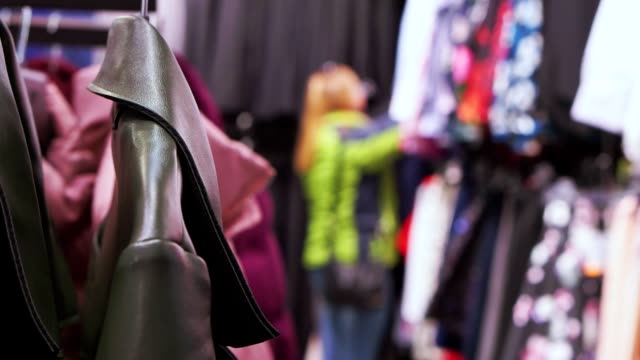 Clothing-store,-look-through-clothes,-woman-chooses-clothes,-she-is-out-of-focus