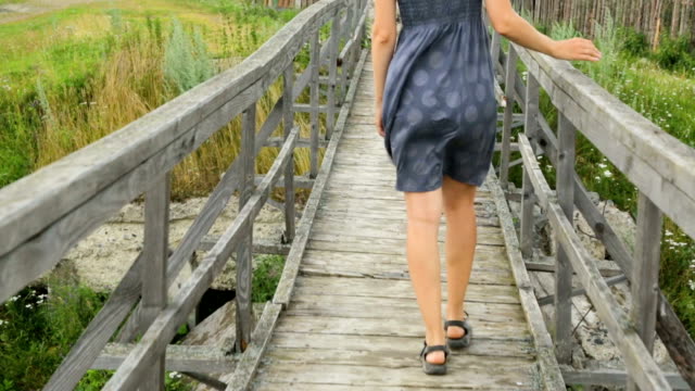Woman-walking-along-old-wooden-bridge