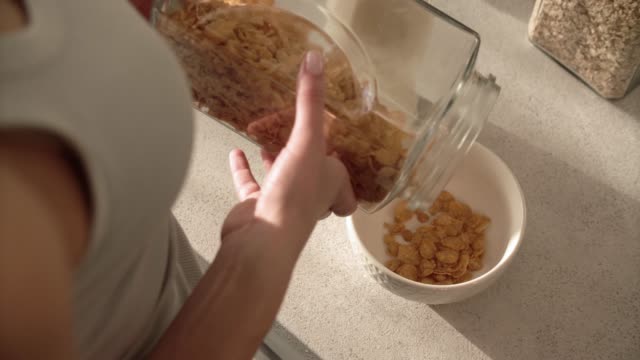 Desayuno-saludable.-Manos-de-mujer-llenando-el-tazón-de-fuente-de-Muesli-de-cereales