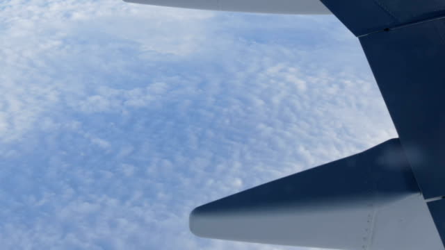 Wing-of-the-plane-through-the-porthole.-The-plane-flies-over-beautiful-air-clouds