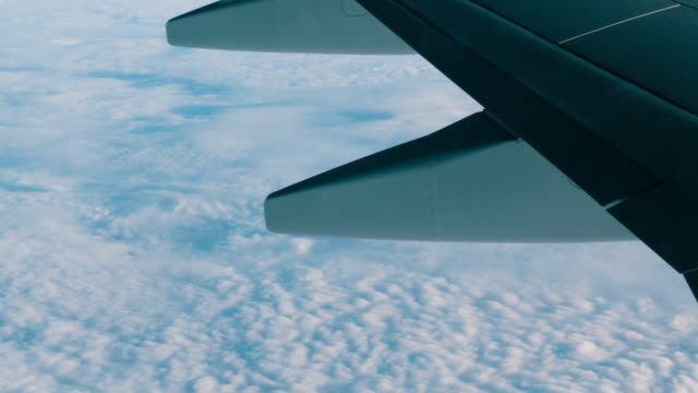 Blick-auf-die-Flügel-eines-Flugzeuges-im-Flug-über-schöne-Luft-Wolken