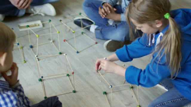 Chicas-haciendo-forma-3D-con-palitos-en-el-jardín-de-la-infancia-lección