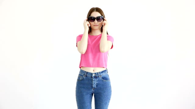 schöne-fröhliche-Mädchen-mit-Sonnenbrille,-Rosa-Top-und-Jeans-posiert-an-weißer-Wand