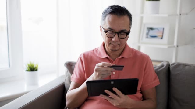 Mann-mit-TabletPC-und-Kreditkarte-zu-Hause-auf-sofa