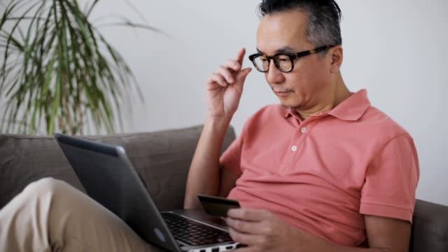 man-with-laptop-and-credit-card-on-sofa-at-home