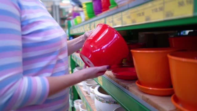 Caucasian-woman-near-shop-shelves-choosing-ceramic-pot-for-household-in-store-closeup