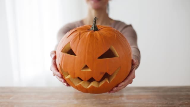 close-up-of-woman-with-halloween-pumpkin-at-home
