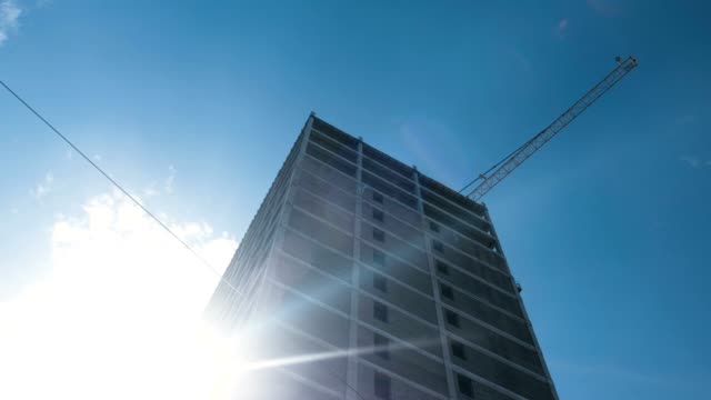 Multi-storey-under-construction-building-and-construction-crane-on-clear-sky-background.