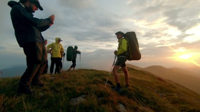 Wanderer-nehmen-Sie-Bilder-auf-einem-Smartphone-bei-Sonnenuntergang-am-Gipfel-des-Berges