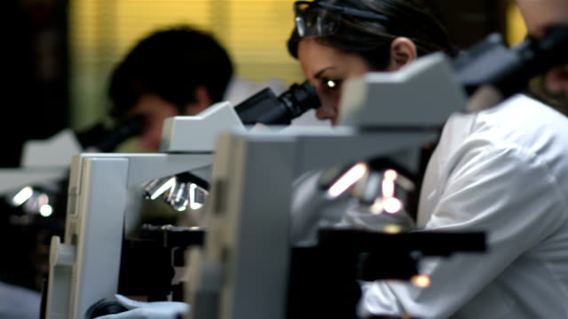 Los-estudiantes-universitarios-en-un-laboratorio-de-mirar-a-través-de-un-microscopio-durante-su-clase