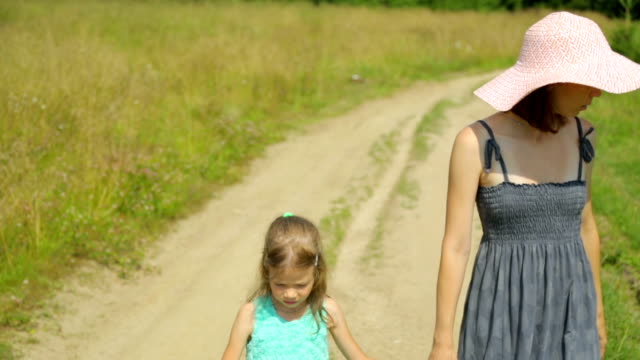 Madre-y-su-hija-caminando-por-un-camino-rural