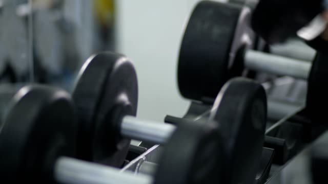 Close-up.-Male-hands-put-dumbbells-on-the-rack-4K-Slow-Mo
