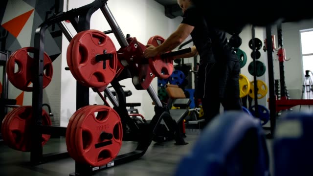 Gym.-A-man-comes-to-the-simulator.-Starts-to-lift-the-weight-with-their-feet-4K-Slow-Mo