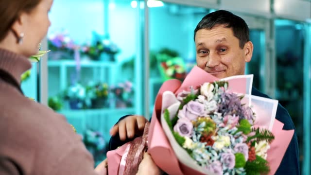Ein-Mann-nimmt-einen-Blumenstrauß-von-einem-Floristen.