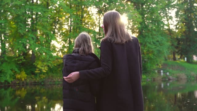 Woman-and-her-daughter-standing-near-the-pond.