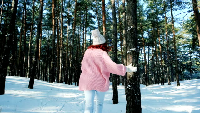 Cute-girl-walking-in-winter-forest,-a-woman-with-red-hair,-running-around-in-the-snow