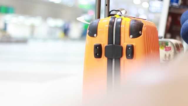 Bolsa-amarilla-de-seguridad-maleta-de-equipaje-de-viaje-de-salida-de-aeropuerto-para-vacaciones-en-blur-avión-terminal-zona-de-espera-para-fondo-de-pasillo-de-pasajeros,-se-centran-en-maletas.