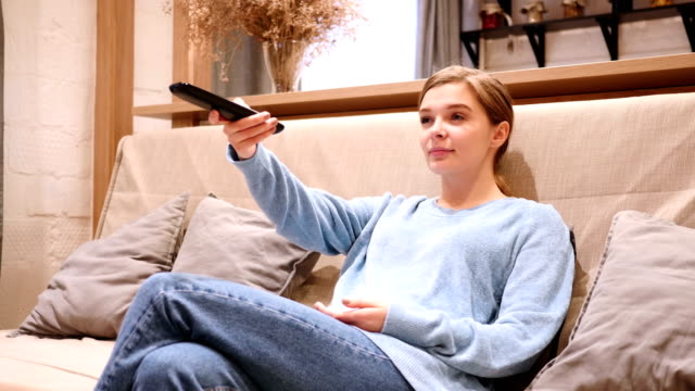 Woman-Watching-TV-and-Changing-Channels,-Sitting-on-Couch