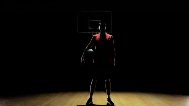 A-basketball-player-dribbles,-then-picks-up-the-ball-and-stares-at-camera.