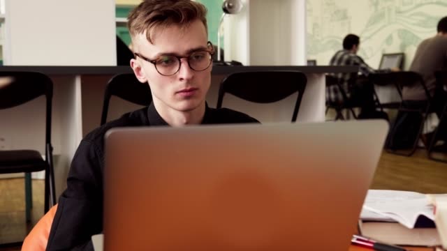 Joven-estudiante-masculino-en-vasos-utilizando-la-laptop-en-la-Universidad