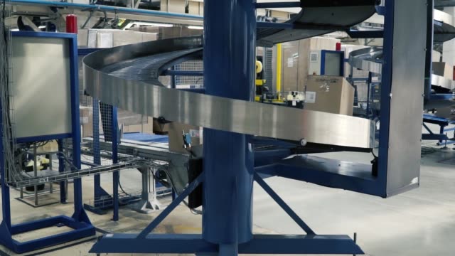 Cardboard-boxes-on-conveyor-belt-in-factory.-Clip.-Production-line-on-which-the-boxes-move-in-a-spiral