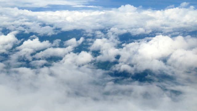 4-K.-Luftaufnahme-durch-ein-Flugzeugfenster.-schöne-weiße-Wolken-im-blauen-Himmelshintergrund.-Reisen-mit-dem-Flugzeug.
